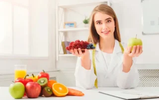 Doctora con ambo médico mostrando opciones de alimentos saludables para cuidar el corazón y prevenir el colesterol alto.