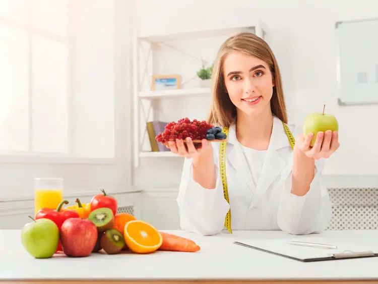 Doctora con ambo médico mostrando opciones de alimentos saludables para cuidar el corazón y prevenir el colesterol alto.