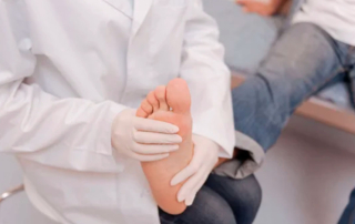 Doctor revisando el pie de un paciente con síntomas de gota